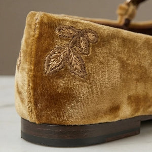 Brown velvet shoe with leaf embroidery on a neutral background