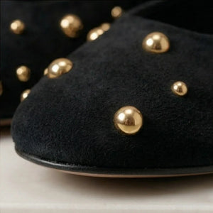 Black shoes with gold studs on a light background