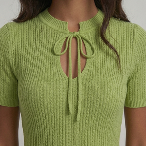 Green knitted top with a tie detail on a plain background