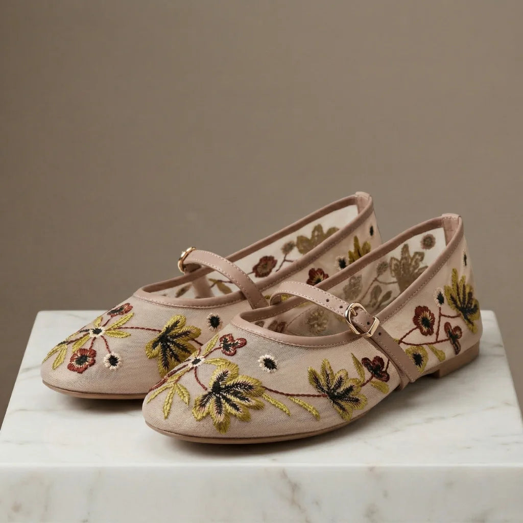 Pair of pink embroidered shoes on a marble surface with a neutral background