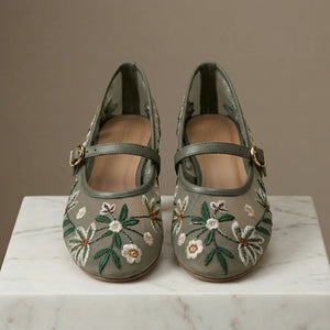 Pair of floral embroidered shoes on a marble surface with a neutral background