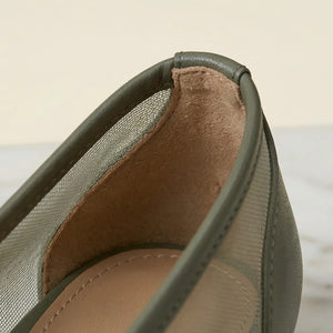 Close-up of a green shoe with brown lining on a light background