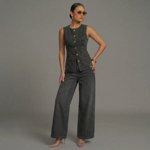 Woman wearing a dark gray sleeveless top and wide-leg pants against a gray background