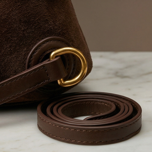 Brown leather strap with gold ring on a marble surface