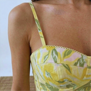 Yellow floral dress with thin straps on a person against a light background