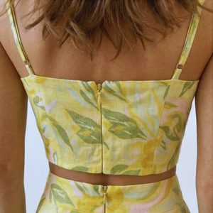 Yellow floral dress with thin straps on a person against a light blue background
