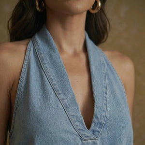 Close-up of a person wearing a light blue denim halter top against a neutral background