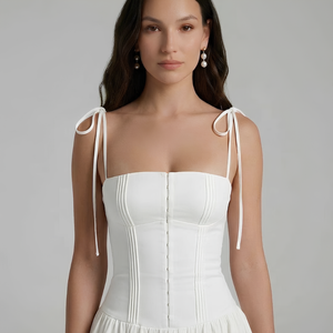 Woman wearing a white dress with thin straps on a gray background