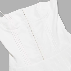 Close-up of a white garment with a zipper detail on a gray background
