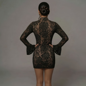 Person wearing a black lace dress against a gray background