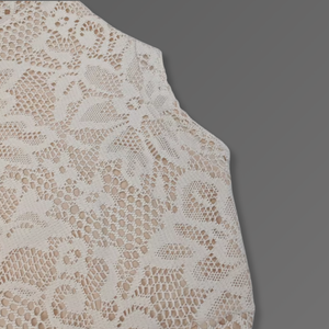 Close-up of beige lace fabric on a gray background