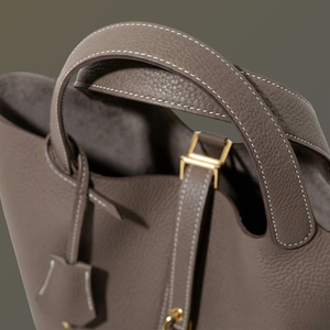 Close-up of a brown leather handbag with a gold clasp on a dark background