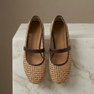 Pair of woven shoes with brown straps on a marble surface
