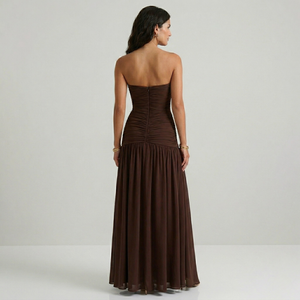 Woman wearing a brown strapless gown on a plain background