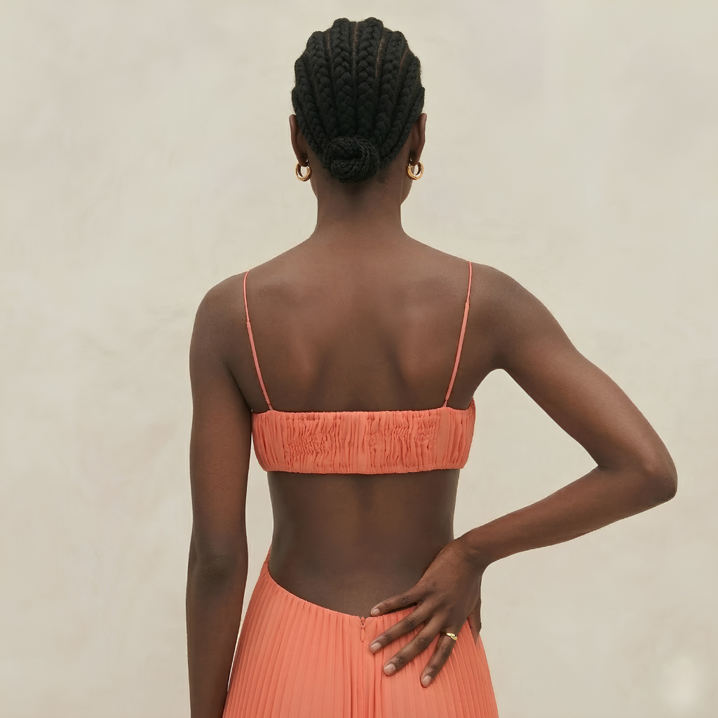 Woman wearing an orange bikini set against a neutral background