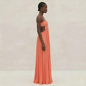 Woman wearing a long coral dress against a plain background