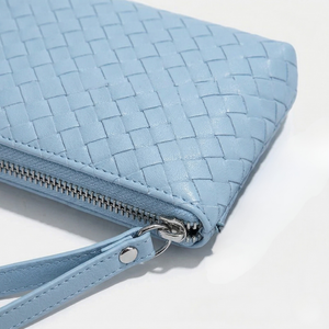 Blue woven handbag with a silver zipper on a white background