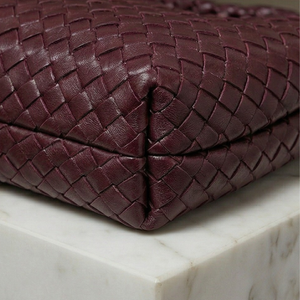 Close-up of a braided brown leather bag on a marble surface