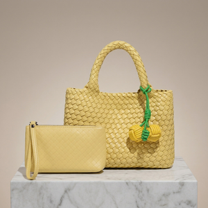 Yellow woven handbag with a matching pouch on a marble surface