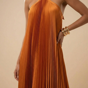 Orange pleated dress worn by a person on a beige background