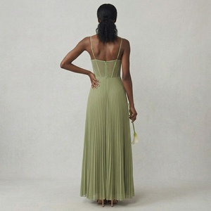Woman wearing a long green dress with thin straps on a plain background