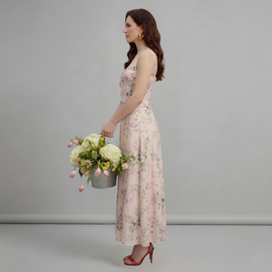 Woman in a floral dress holding a bouquet of flowers against a plain background