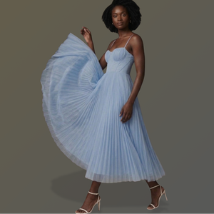 Woman wearing a light blue pleated dress on a gray background