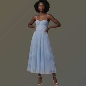 Woman wearing a light blue pleated dress on a dark background