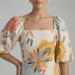 Woman wearing a floral blouse with colorful patterns on a plain background