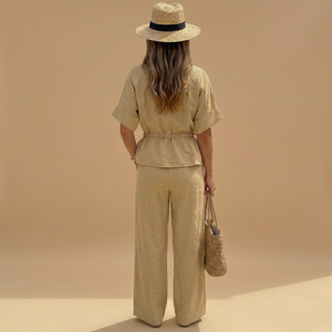 Woman in beige outfit with hat and bag against a beige background