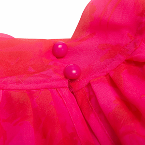 Close-up of a bright pink garment with buttons on a white background