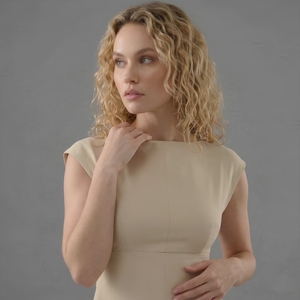 Woman wearing a beige dress against a gray background