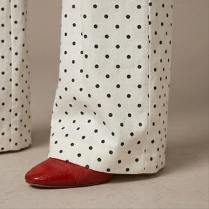 White pants with black polka dots and red shoes on a beige background