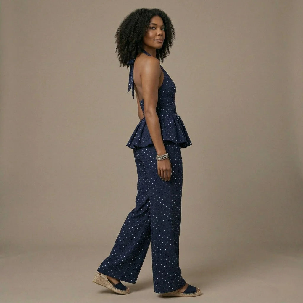 Woman wearing a navy blue polka dot peplum top and wide-leg pants on a beige background