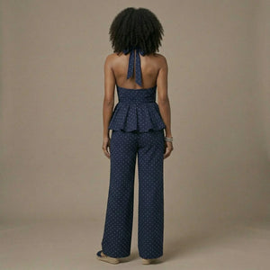 Woman wearing a navy polka dot peplum top and wide-leg pants on a beige background