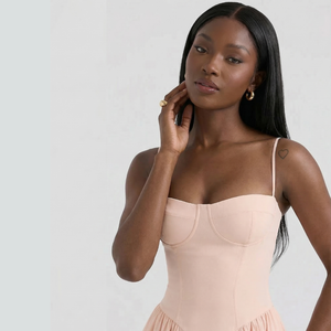 Woman wearing a beige dress against a plain background