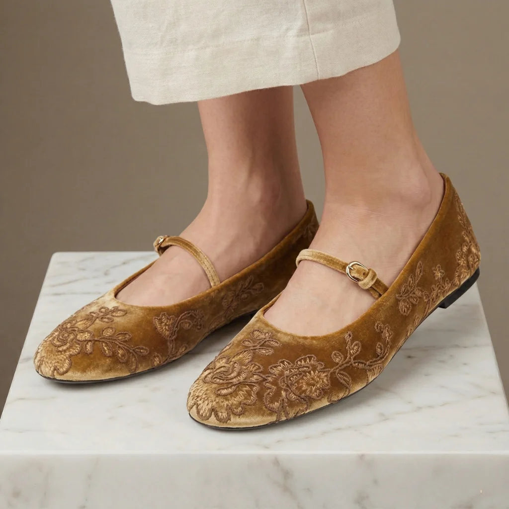 Brown embroidered flats on a marble surface with a neutral background