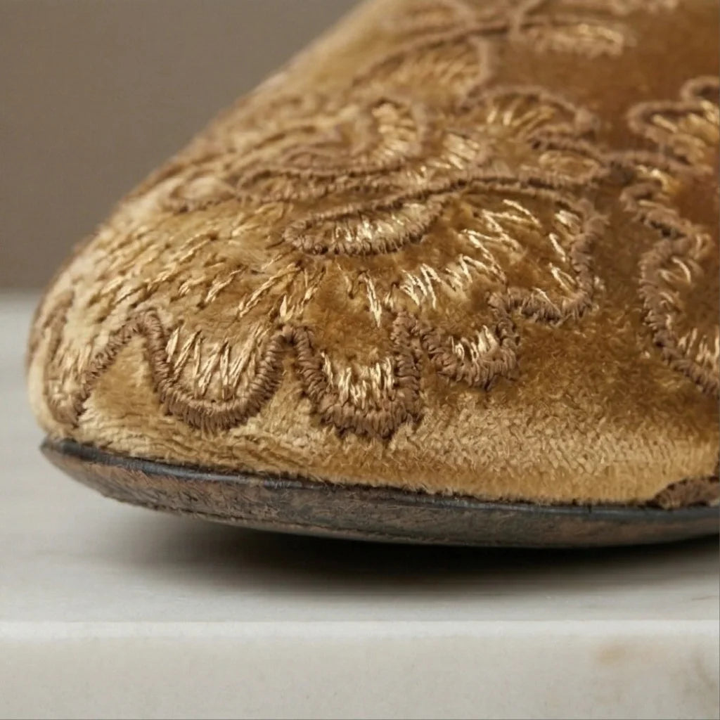 Close-up of a brown embroidered shoe on a neutral background