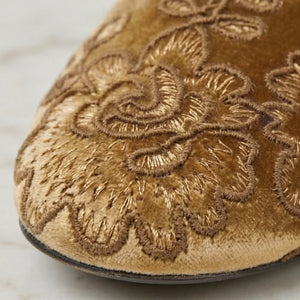 Close-up of a gold embroidered shoe on a light background