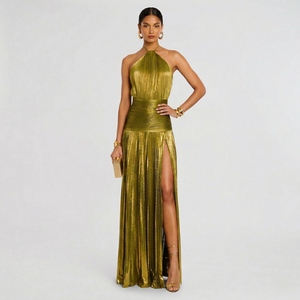 Woman wearing a gold evening gown with a high slit on a light gray background