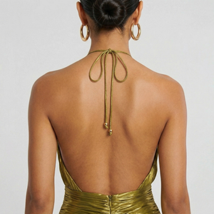 Gold dress with open back and hoop earrings on a plain background