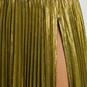 Close-up of a gold pleated skirt with a plain background