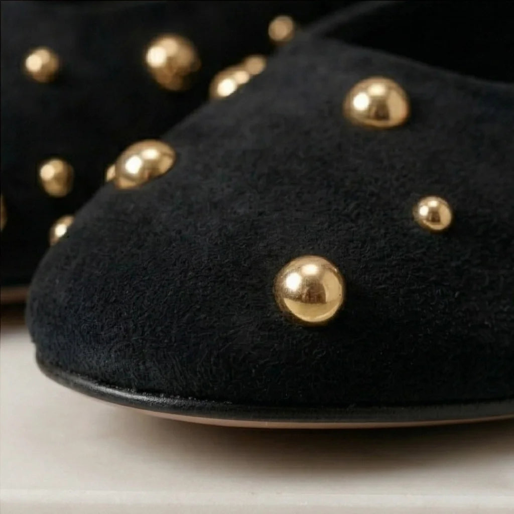 Black shoes with gold studs on a light background