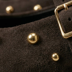 Close-up of a brown leather bag with gold studs and buckle