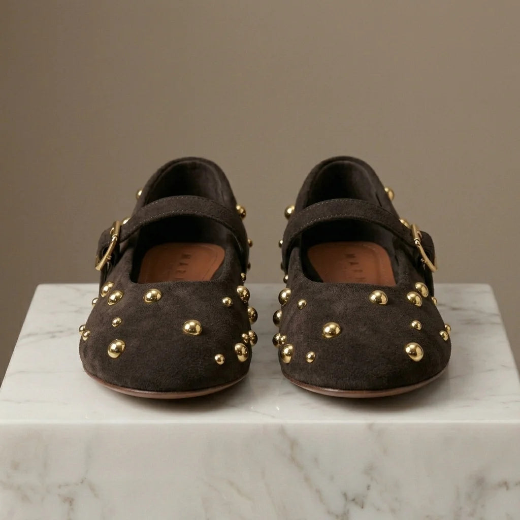 Pair of brown suede shoes with gold studs on a marble surface.