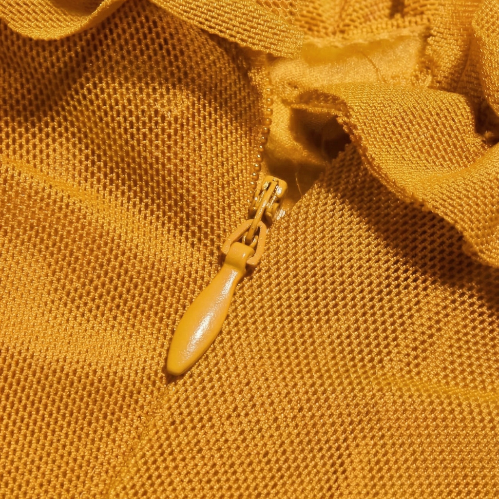 Close-up of a yellow zipper on textured yellow fabric