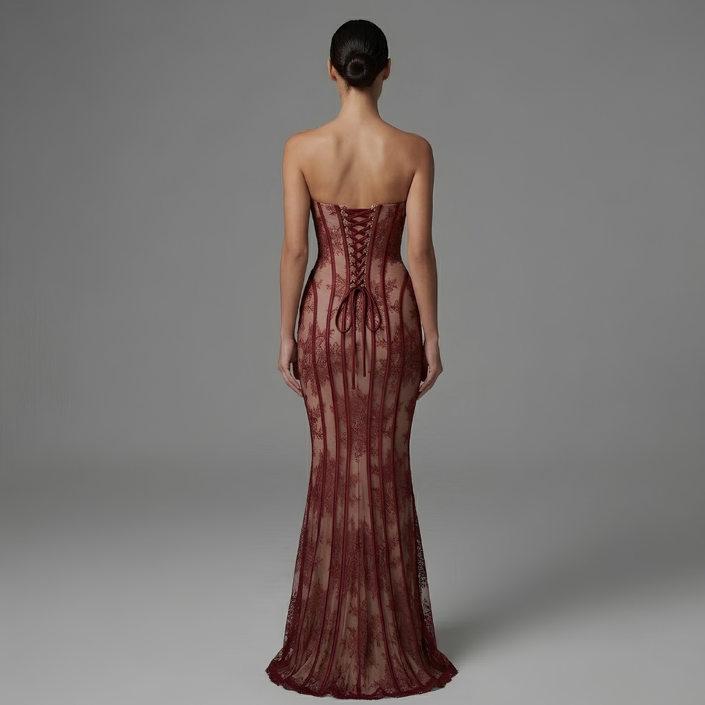 Woman wearing a burgundy strapless gown with lace detailing on a gray background