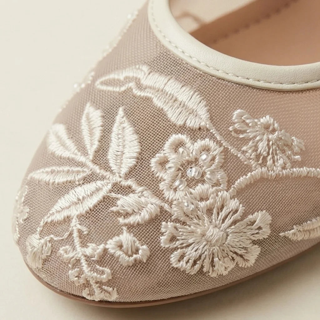 Beige shoe with white floral embroidery on a light background