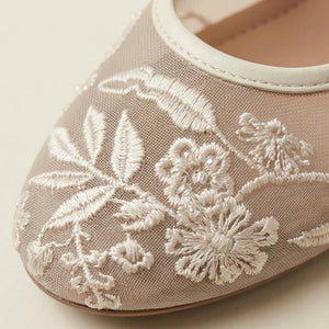 Beige shoe with white floral embroidery on a light background