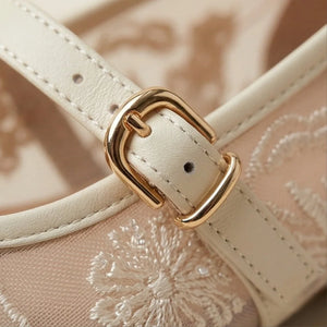 Close-up of a beige handbag with a gold buckle on an embroidered background